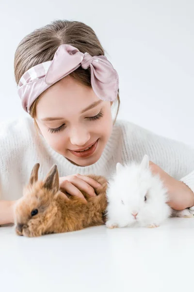 Happy child playing with adorable furry rabbits on white — Stock Photo