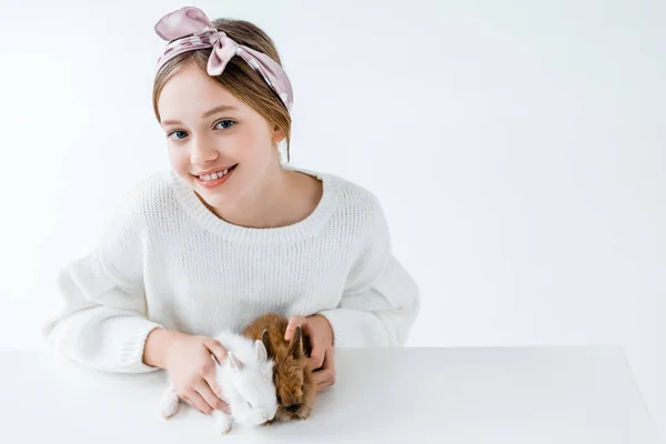 Menina bonita segurando adoráveis coelhos peludos e sorrindo para a câmera no branco — Fotografia de Stock