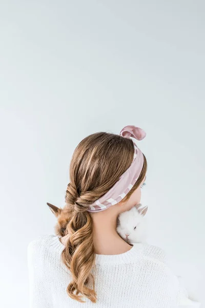 Visão traseira da menina segurando adoráveis coelhos peludos isolados no branco — Fotografia de Stock