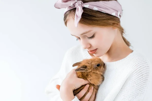 Vista de cerca de un niño lindo sosteniendo adorable conejo peludo aislado en blanco - foto de stock