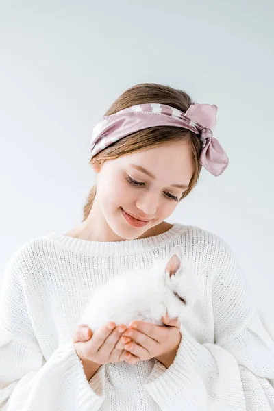 Hermosa chica sonriente sosteniendo peludo conejo blanco aislado en blanco - foto de stock