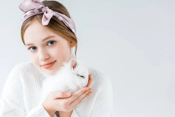 Adorabile bambino tenendo peloso coniglio bianco e guardando la fotocamera isolata su bianco — Foto stock