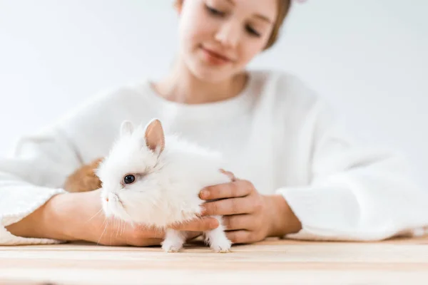 Selective focus of smiling girl holding cute furry rabbit on white — Stock Photo
