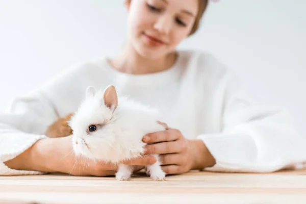 Selektiver Fokus eines lächelnden Mädchens, das niedliche pelzige Kaninchen auf Weiß hält — Stockfoto