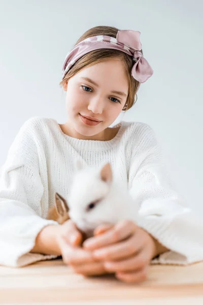 Enfoque selectivo de la chica sonriente sosteniendo lindos conejos peludos en blanco - foto de stock