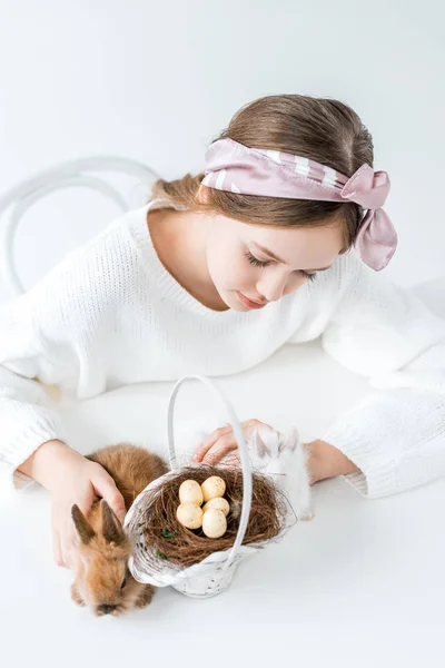Vue grand angle de fille regardant les lapins et le panier avec des œufs de Pâques dans le nid — Photo de stock