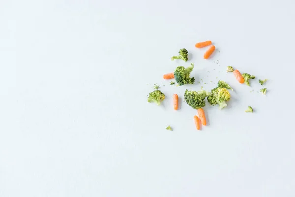 Vista superior de zanahorias frescas crudas maduras y brócoli sobre blanco - foto de stock