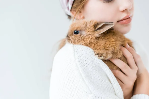 Recortado disparo de niño sosteniendo lindo conejo peludo aislado en blanco - foto de stock