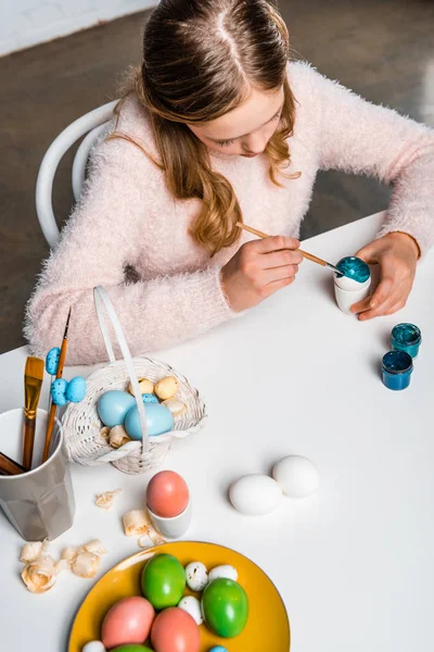 Vista de ángulo alto de lindo niño enfocado pintura huevo de Pascua en la mesa - foto de stock