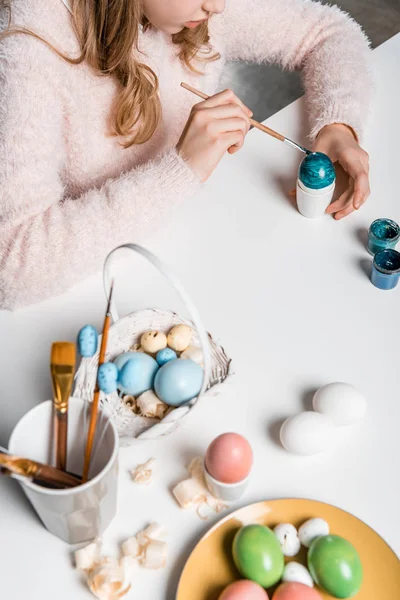 Plan recadré d'adorable enfant peignant des oeufs de Pâques à table — Photo de stock