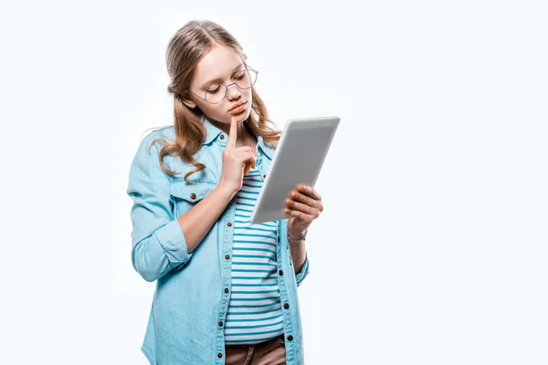 Muchacha adolescente pensativa en gafas usando tableta digital aislada en blanco - foto de stock