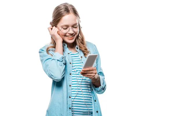 Adorable fille heureuse dans les écouteurs en utilisant smartphone isolé sur blanc — Photo de stock