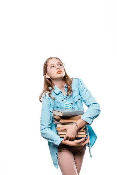 Bonito adolescente menina no óculos segurando pilha de livros e olhando para cima isolado no branco — Fotografia de Stock
