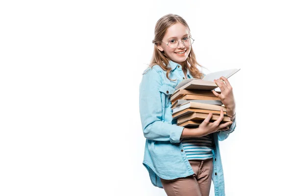 Bela adolescente em óculos segurando pilha de livros e sorrindo para a câmera isolada no branco — Fotografia de Stock