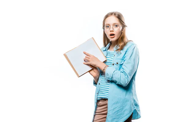 Menina chocada em óculos apontando para livro em branco e olhando para a câmera isolada no branco — Fotografia de Stock