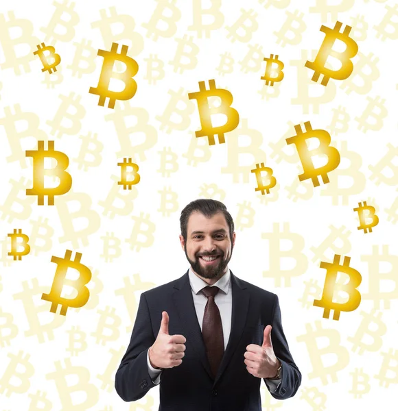 Barbudo sonriente hombre de negocios en traje mostrando los pulgares hacia arriba y bitcoin símbolos aislados en blanco - foto de stock