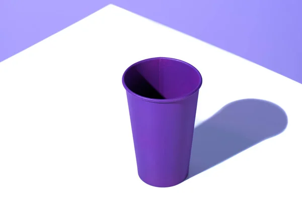 Taza desechable de plástico púrpura, en la superficie blanca - foto de stock