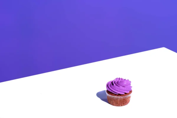 Cupcake with purple buttercream glaze, on white surface — Stock Photo