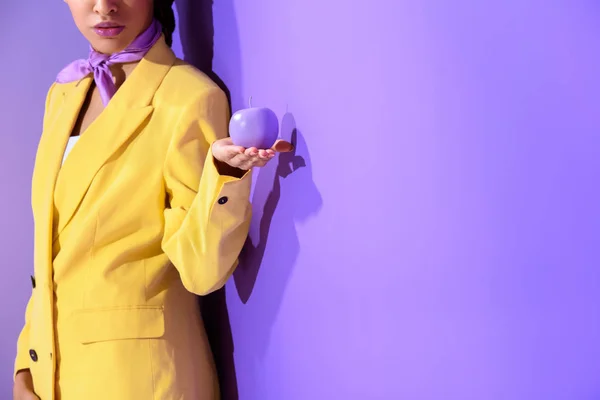 Cropped view of girl in yellow suit with purple apple, on trendy ultra violet background — Stock Photo