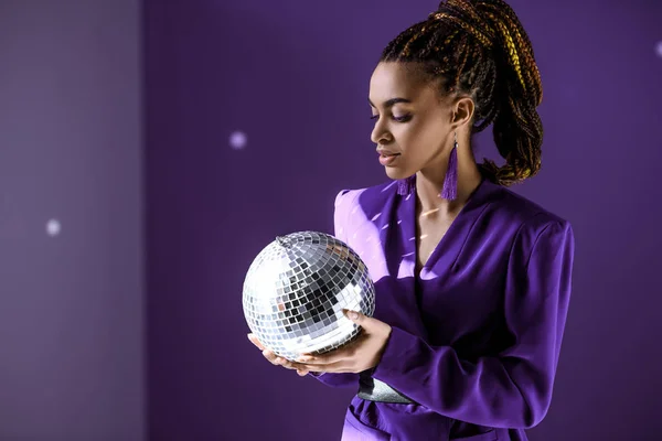 Stylish mulatto model posing in purple jacket with disco ball, ultra violet trend — Stock Photo