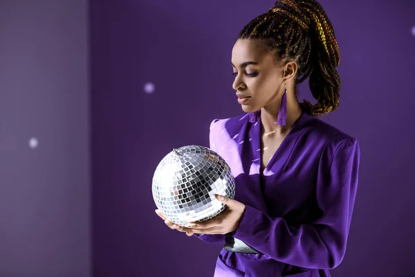 Modelo mulato elegante posando em casaco roxo com bola de discoteca, tendência ultravioleta — Fotografia de Stock