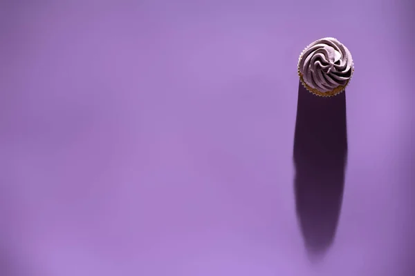 Вид сверху на кекс с фиолетовой глазурью с тенью, ультрафиолетовый тренд — стоковое фото