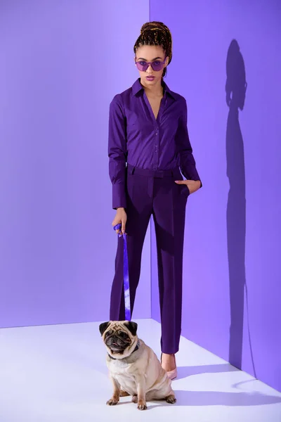 Beautiful african american model posing in purple suit with pug, ultra violet trend — Stock Photo