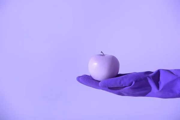 Обрізаний вид на руку в гумовій рукавичці, що тримає фіолетове яблуко, ізольовано на ультрафіолетовому — стокове фото