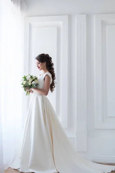 Noiva posando em vestido branco elegante com buquê de casamento — Fotografia de Stock