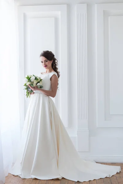 Noiva sorridente posando em vestido elegante com buquê de casamento — Fotografia de Stock