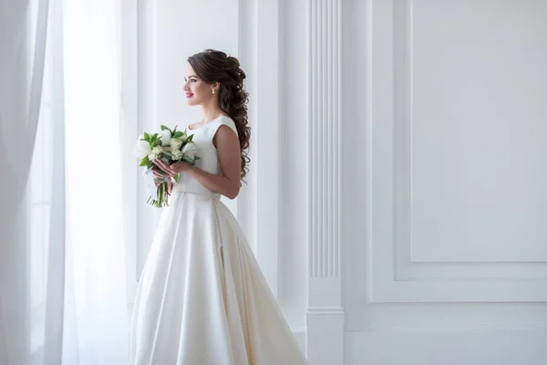 Приваблива щаслива наречена позує в традиційній сукні з весільним букетом — стокове фото