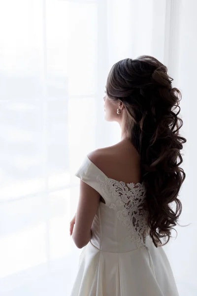 Vista trasera de la novia en vestido de novia mirando a la ventana - foto de stock