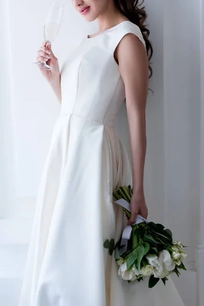 Обрізаний вид на наречену в елегантній сукні з весільним букетом і келихом шампанського — стокове фото