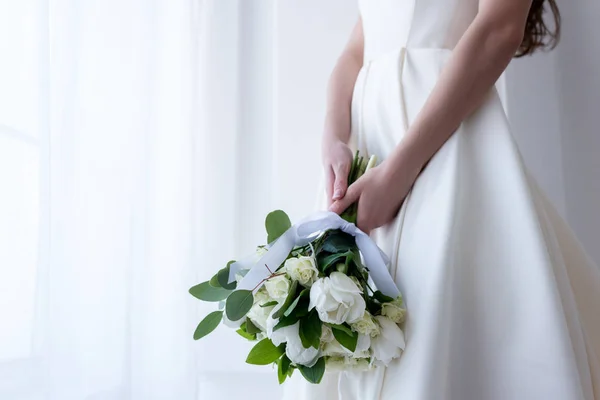 Vista cortada da noiva em vestido tradicional segurando buquê de casamento — Fotografia de Stock