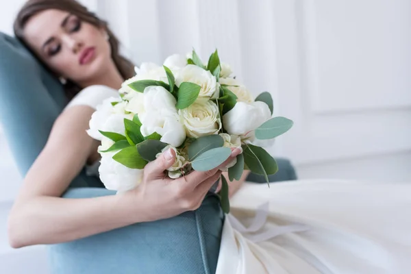 Селективное внимание невесты со свадебным букетом, сидящей в кресле — стоковое фото