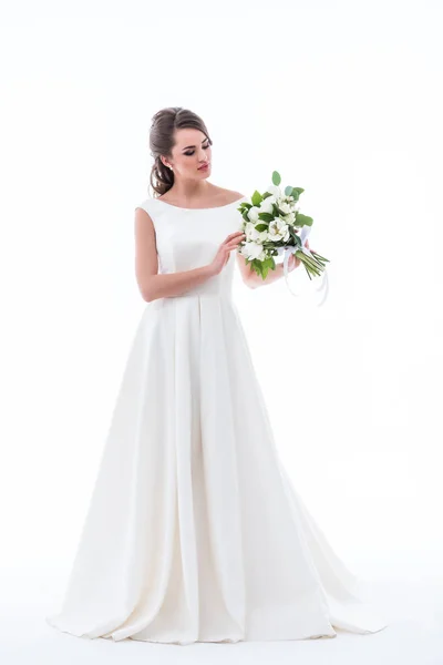 Красивая невеста позирует в традиционном белом платье со свадебным букетом, изолированный на белом — стоковое фото
