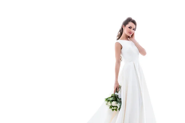 Улыбающаяся невеста позирует в традиционном белом платье со свадебным букетом, изолированная на белом — стоковое фото