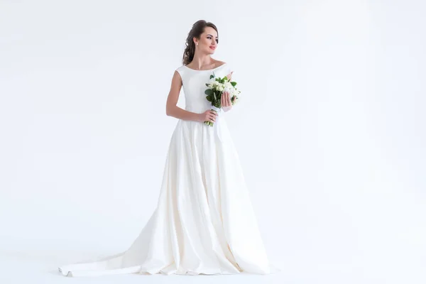 Beautiful brunette bride posing in white dress with wedding bouquet, isolated on white — Stock Photo