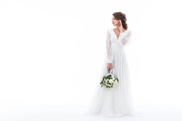Невеста позирует в элегантном белом платье со свадебным букетом, изолированный на белом — стоковое фото