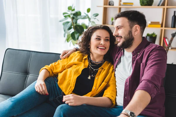 Felice coppia sorridente seduta sul divano in pelle — Foto stock