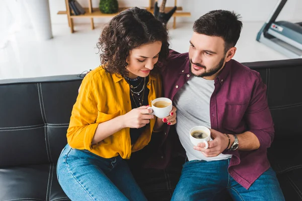 Vista de pareja joven sosteniendo tazas de café - foto de stock