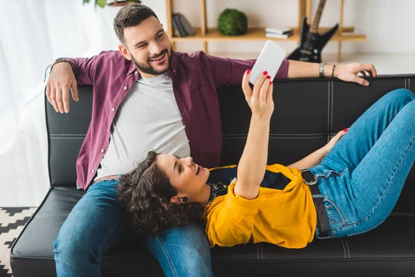 Mujer acostada sobre las rodillas del novio y tomando selfie en el teléfono inteligente - foto de stock