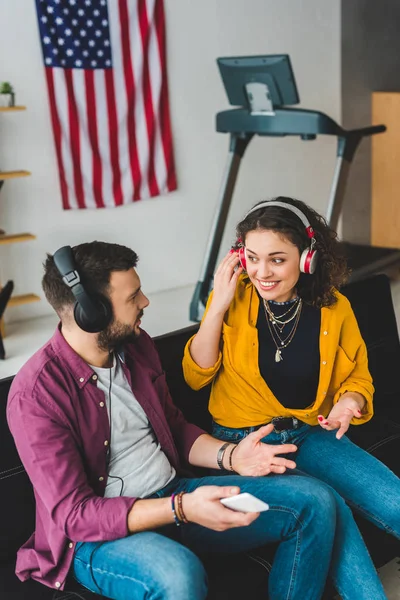 Vista di coppia ascoltare musica in cuffia e seduto sul divano — Foto stock