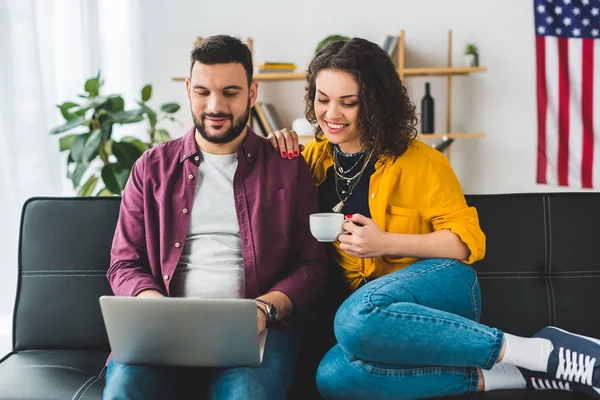 Mann benutzt Laptop, während Frau Tasse Kaffee hält — Stockfoto