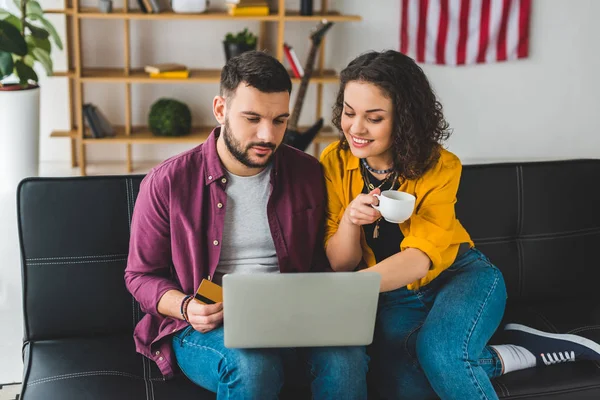 Donna che indica lo schermo del computer portatile mentre l'uomo seduto accanto — Foto stock