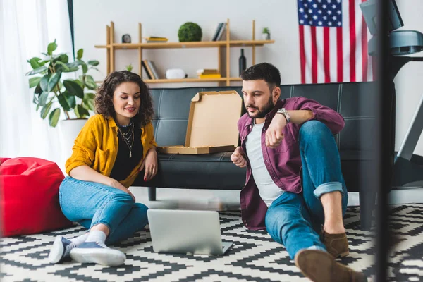 Young couple watching laptop and sitting on floor — Stock Photo