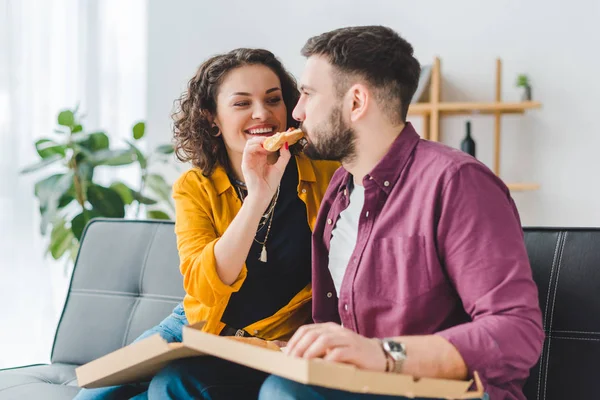 Улыбающаяся женщина кормит своего парня пиццей — стоковое фото
