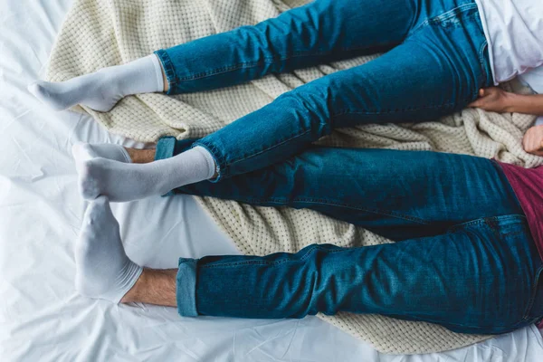 Частичный вид молодой пары лежащей на кровати — стоковое фото