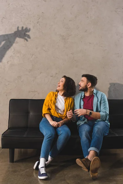 Sombra en la pared y pareja sentada en el sofá - foto de stock