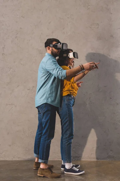 Casal de pé e usando fone de ouvido realidade virtual — Fotografia de Stock